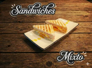 Dos sandwiches mixtos en un plato blanco sobre una mesa de madera.