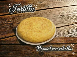 Tortilla española sobre un plato blanco, con un fondo de madera.